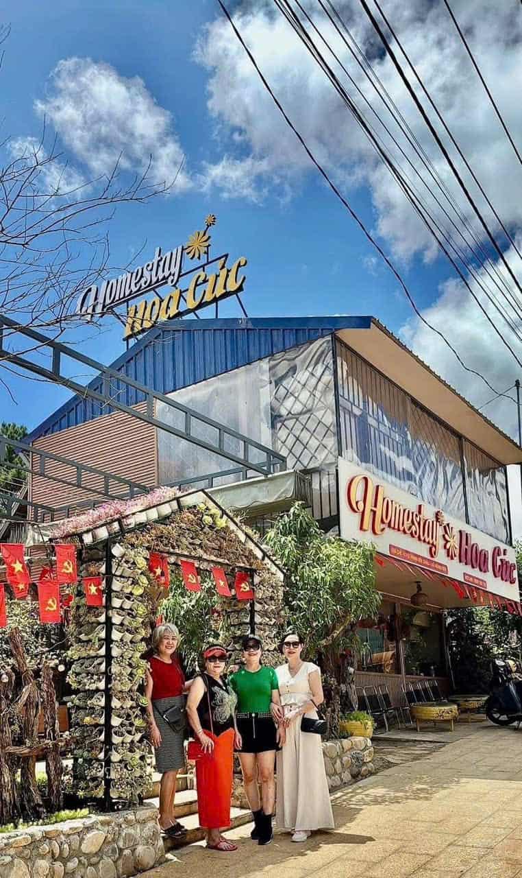 homestay Măng Đen đoàn khách checkin trước cổng homestay hoa cúc