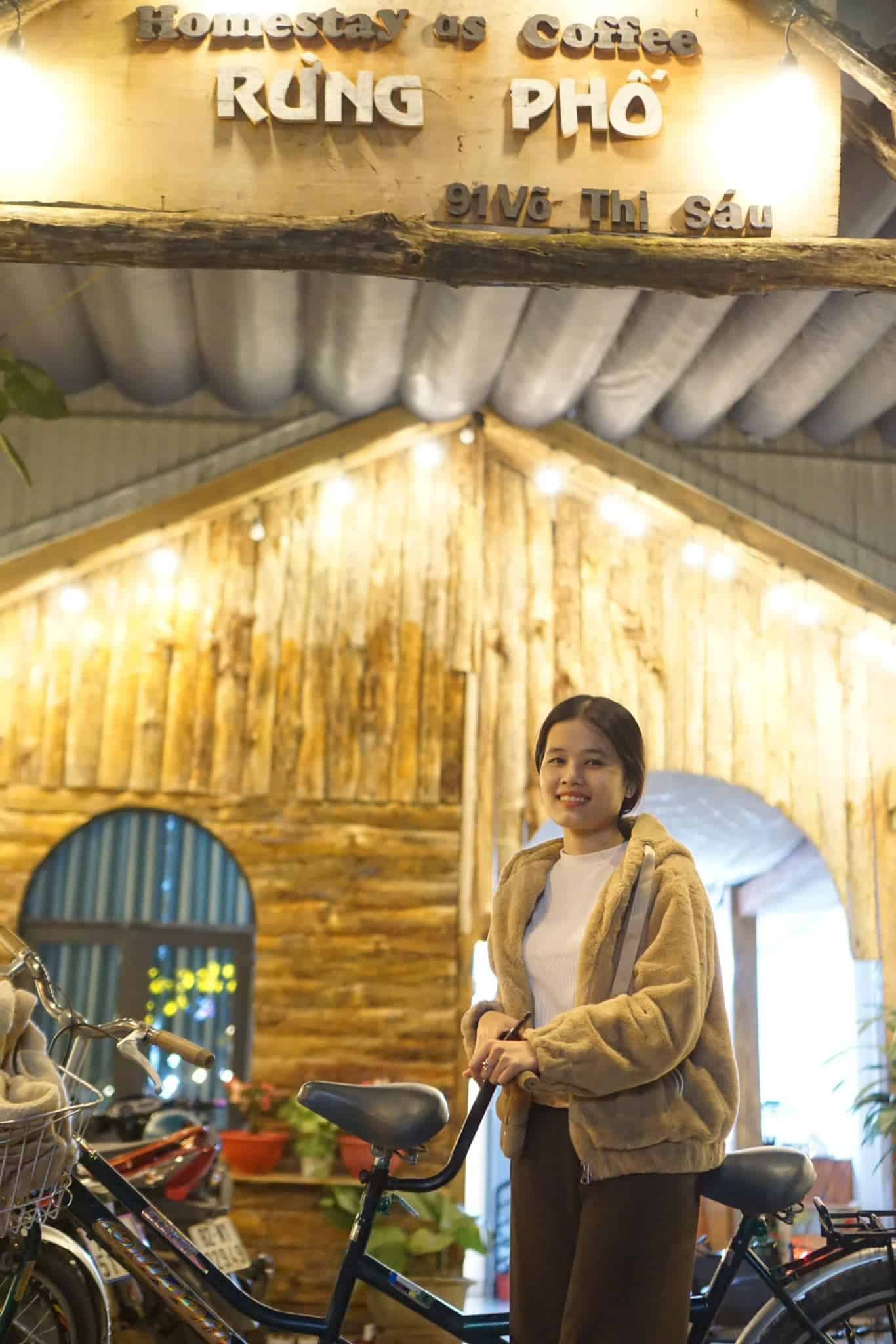 homestay Măng Đen cô gái chụp ảnh cùng xe đạp checkin trước cổng Rừng Phố homestay