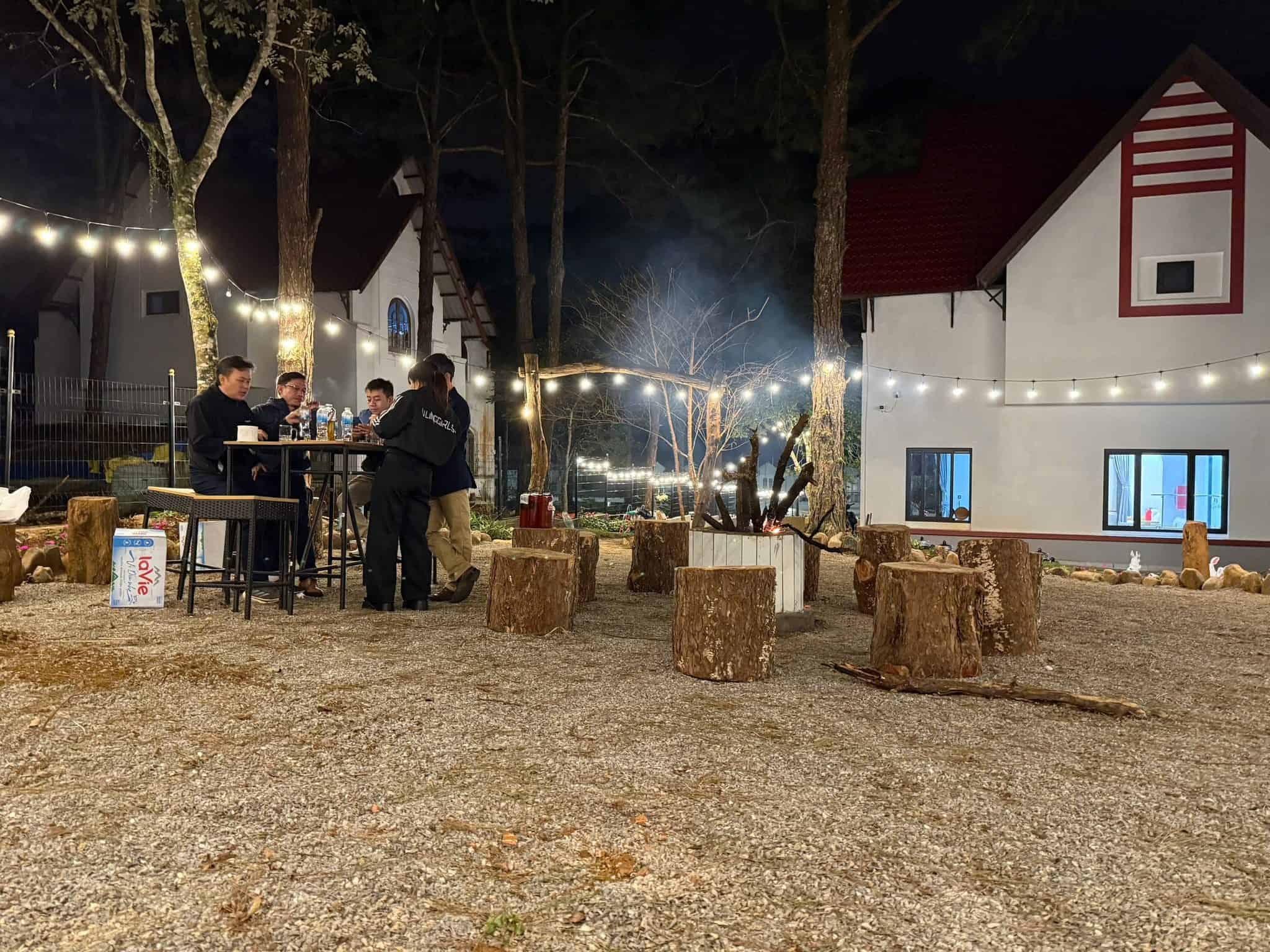 homestay mang den khách ngồi ăn uống ở vườn có bàn ghế gỗ ở Măng Đen Romantic Homestay