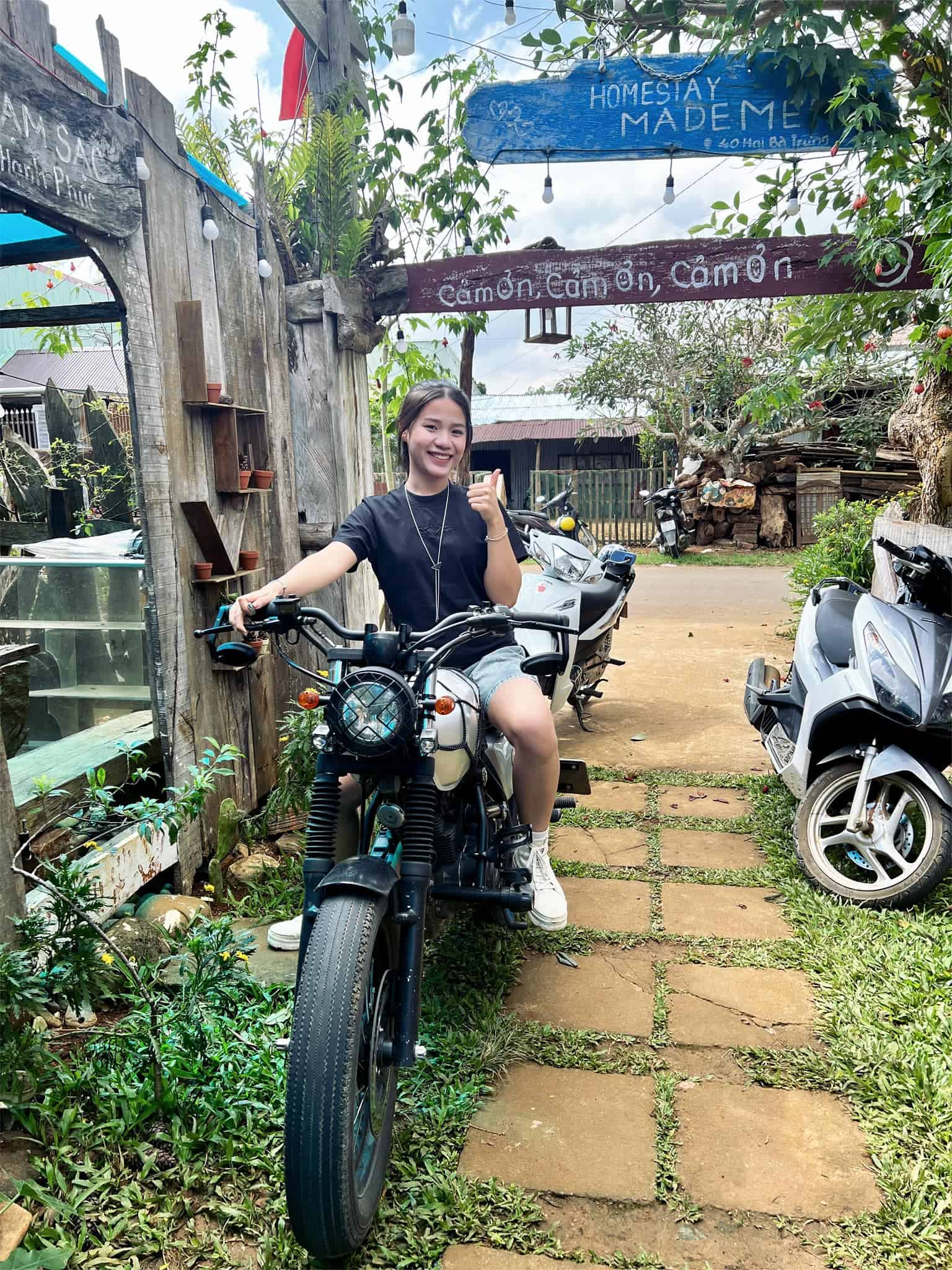 homestay mang den cô gái chụp hình với xe máy trước bảng chữ tiễn khách ở Người Măng Đen Homestay
