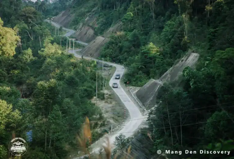 đường đèo Măng Đen tour 3n2d măng đen có xe ô tô đang di chuyển trên đèo, xung quanh là rừng núi di chuyển từ Hà Nội đến Măng Đen