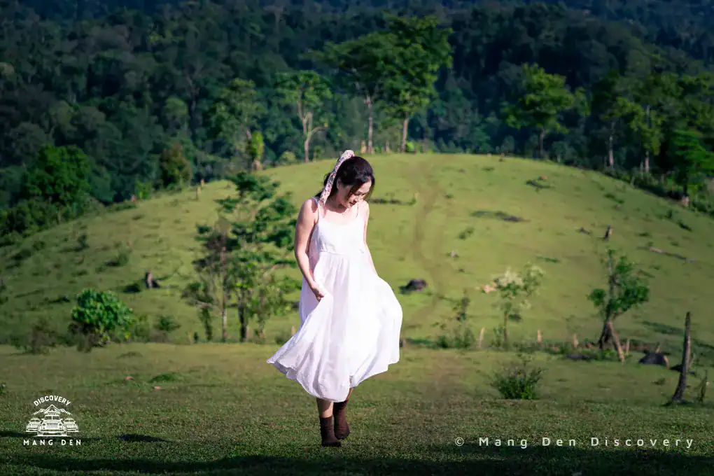 cô gái do bước trên đồi cỏ Kon Vơng Kia phía sau là rừng cây vào sáng sớm