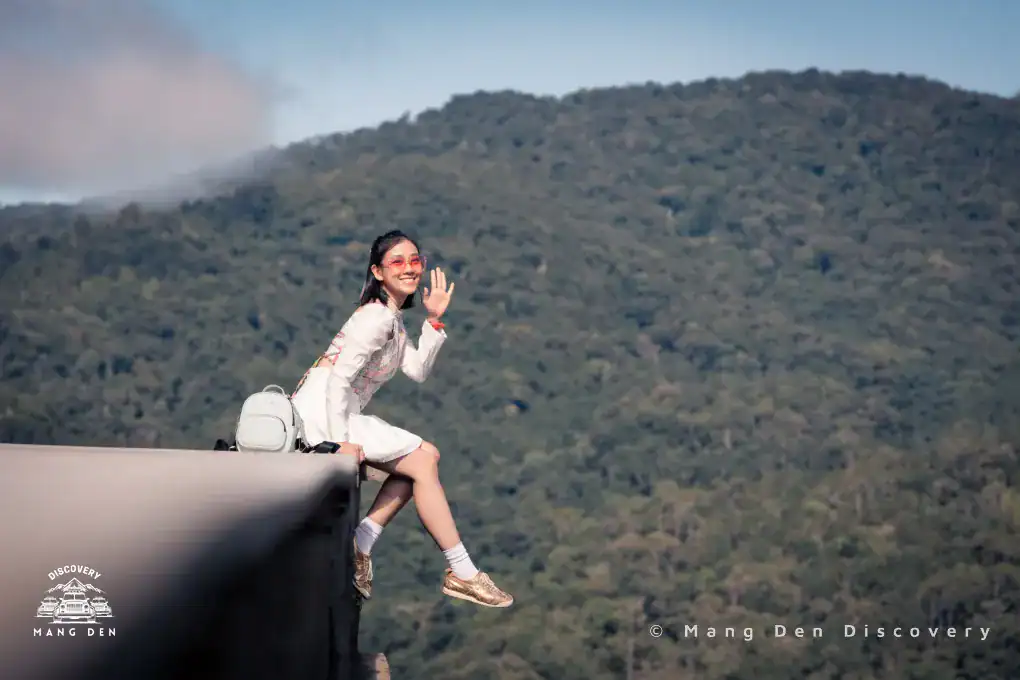 cô gái ngồi chụp ảnh trên mép sàn gỗ với sau lưng là rừng núi Kon Tu Rằng hùng vĩ tại Măng Đen trong lịch trình Măng Đen tour 2n1d