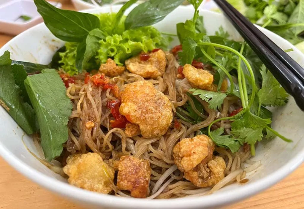 Cận cảnh tô phở khô tại Phở Khô 79 Măng Đen với tóp mỡ, rau sống và sợi phở trộn