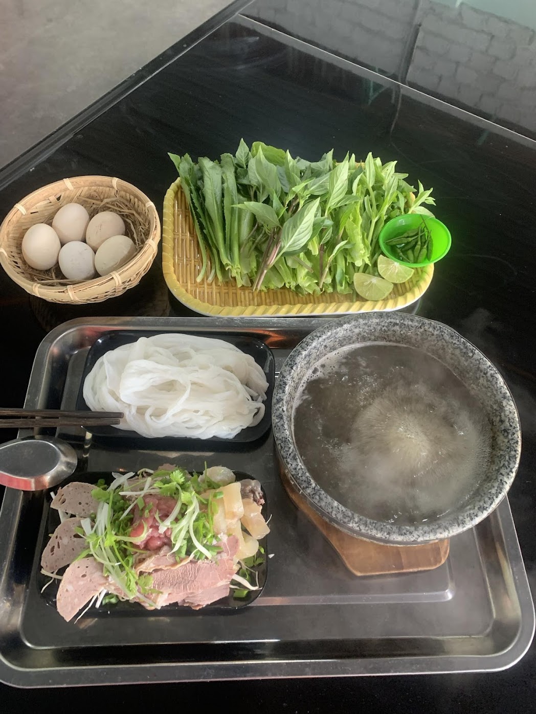 một phần phở bát đá Măng Đen với bát đá sôi, bánh phở, thịt bò và rổ rau