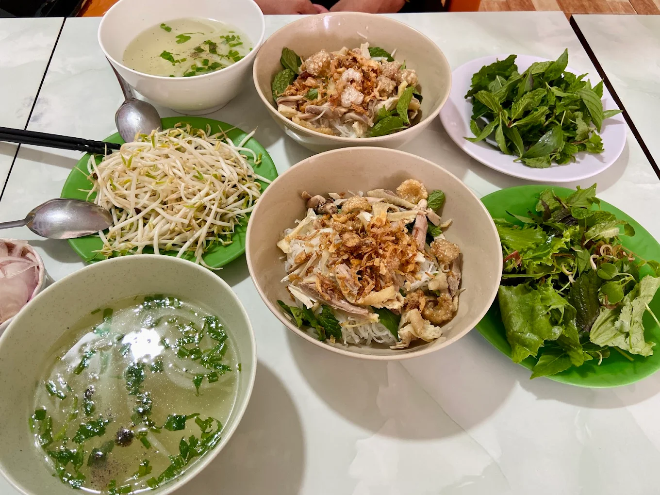 Bữa phở khô đầy đủ tại Quán Bà Bảy Măng Đen với hai tô, rau sống, giá đỗ và nước dùng