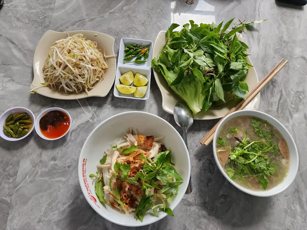 Một phần phở khô 79 Măng Đen đầy đủ với rau sống, giá đỗ và tô nước dùng